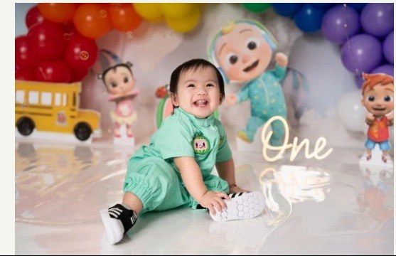 Toddler laughing at a colourful cake smash themed photoshoot