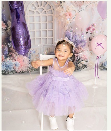 Toddler in a purple tulle dress at a cake smash birthday photoshoot