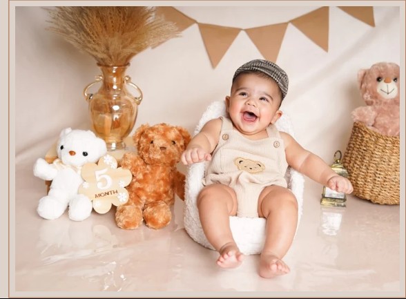 Smiling baby sitting with teddy bears celebrating a monthly milestone