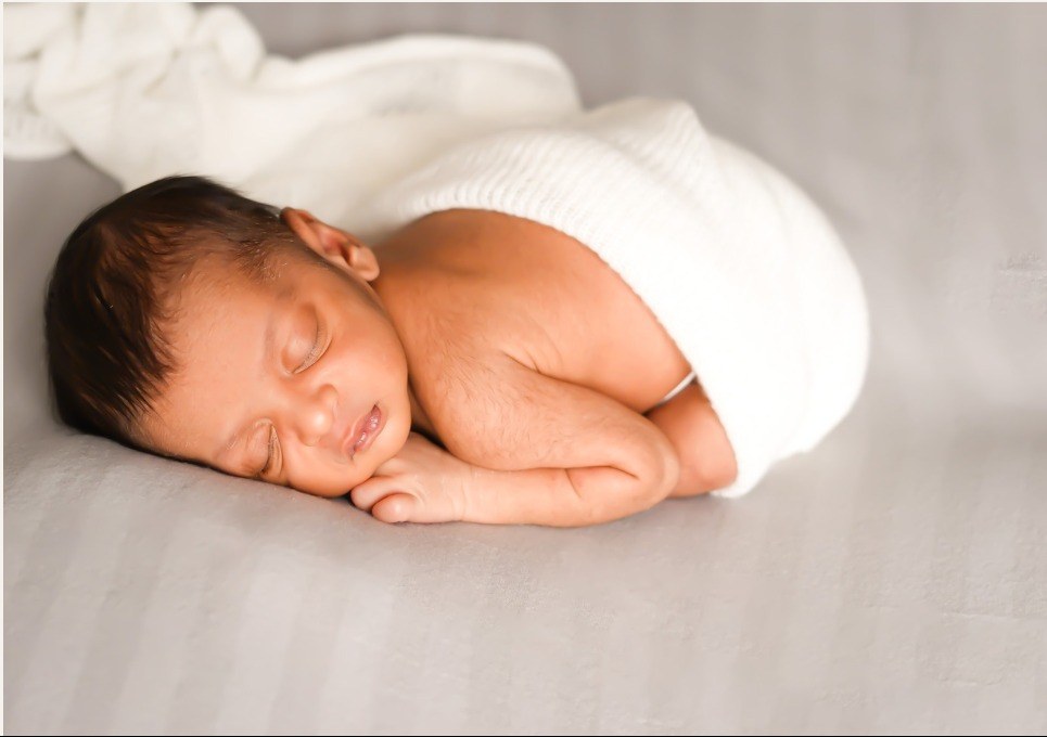 Sleeping newborn baby swaddled in white fabric